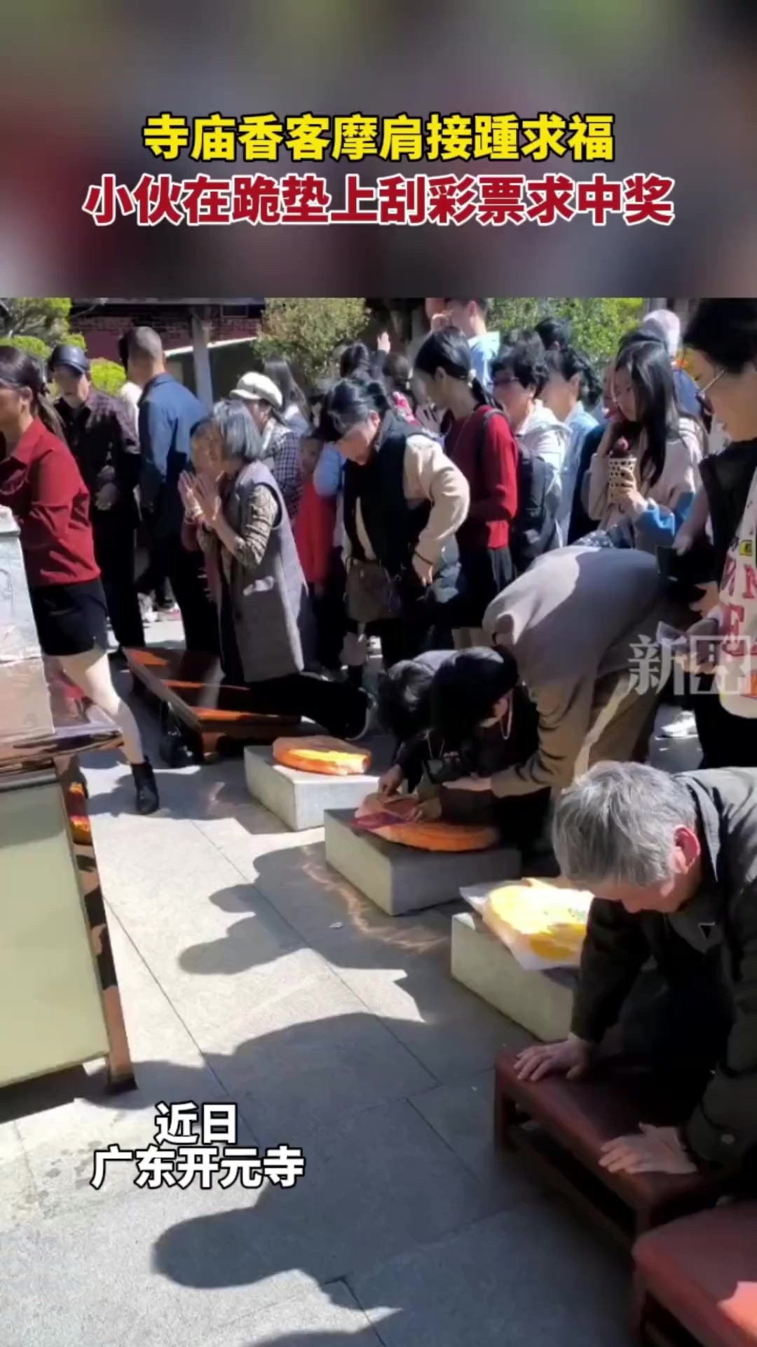 寺庙香客摩肩接踵求福,小伙在跪垫上刮彩票求中奖.