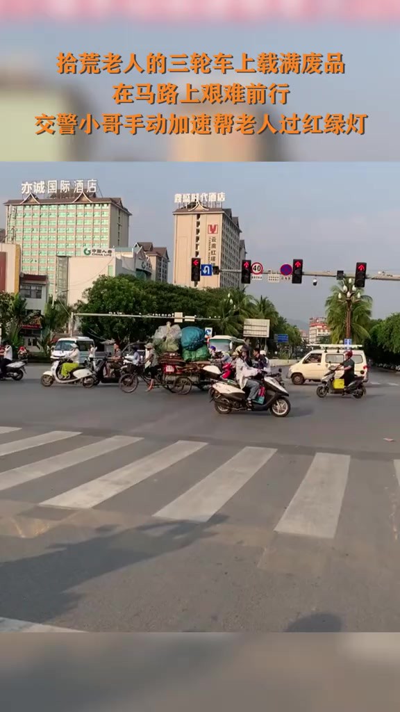 近日,云南,拾荒老人的三轮车上载满废品在马路上艰难前行,交警小哥手动加速帮老人过红绿灯(来源:广东新闻频道)