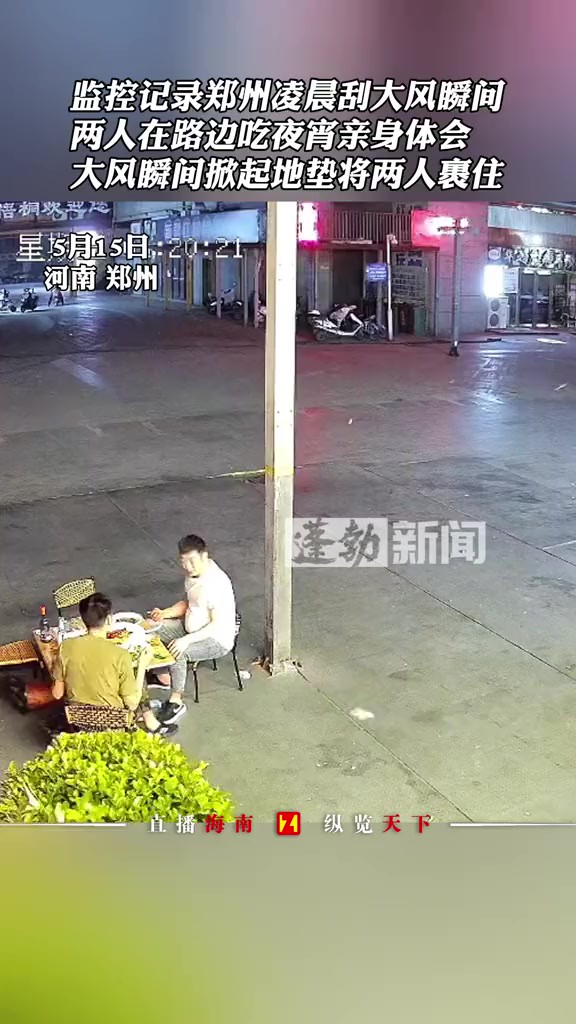 监控记录郑州凌晨刮大风瞬间,两人在路边吃夜宵亲身体会,大风瞬间掀起地垫将两人裹住